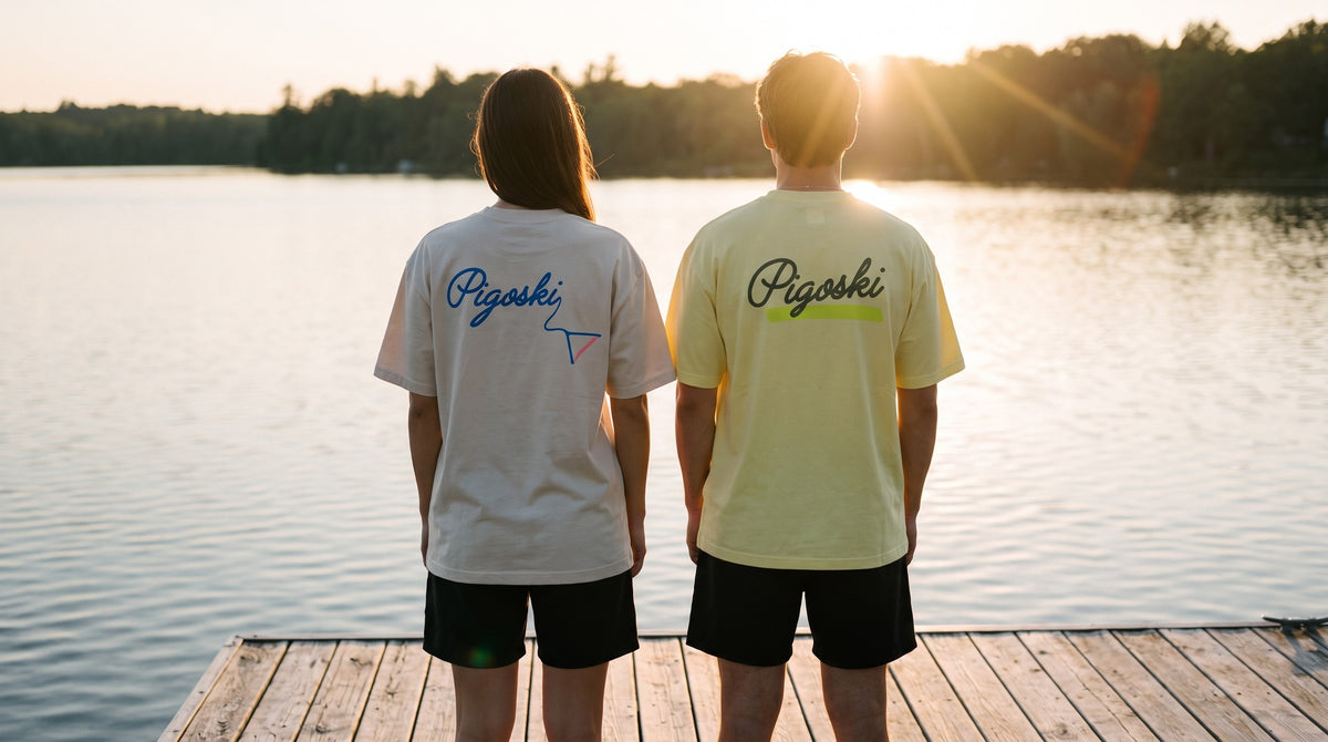 Two friends in PIGOSKI tees on a lake dock at golden hour